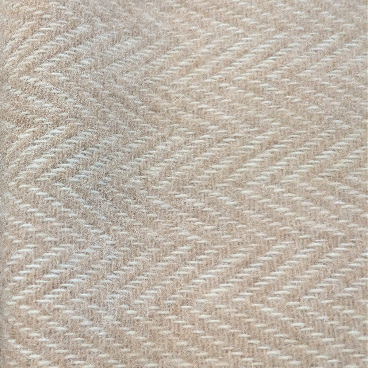 Close-up of fawn cream woven alpaca textile with a herringbone pattern.