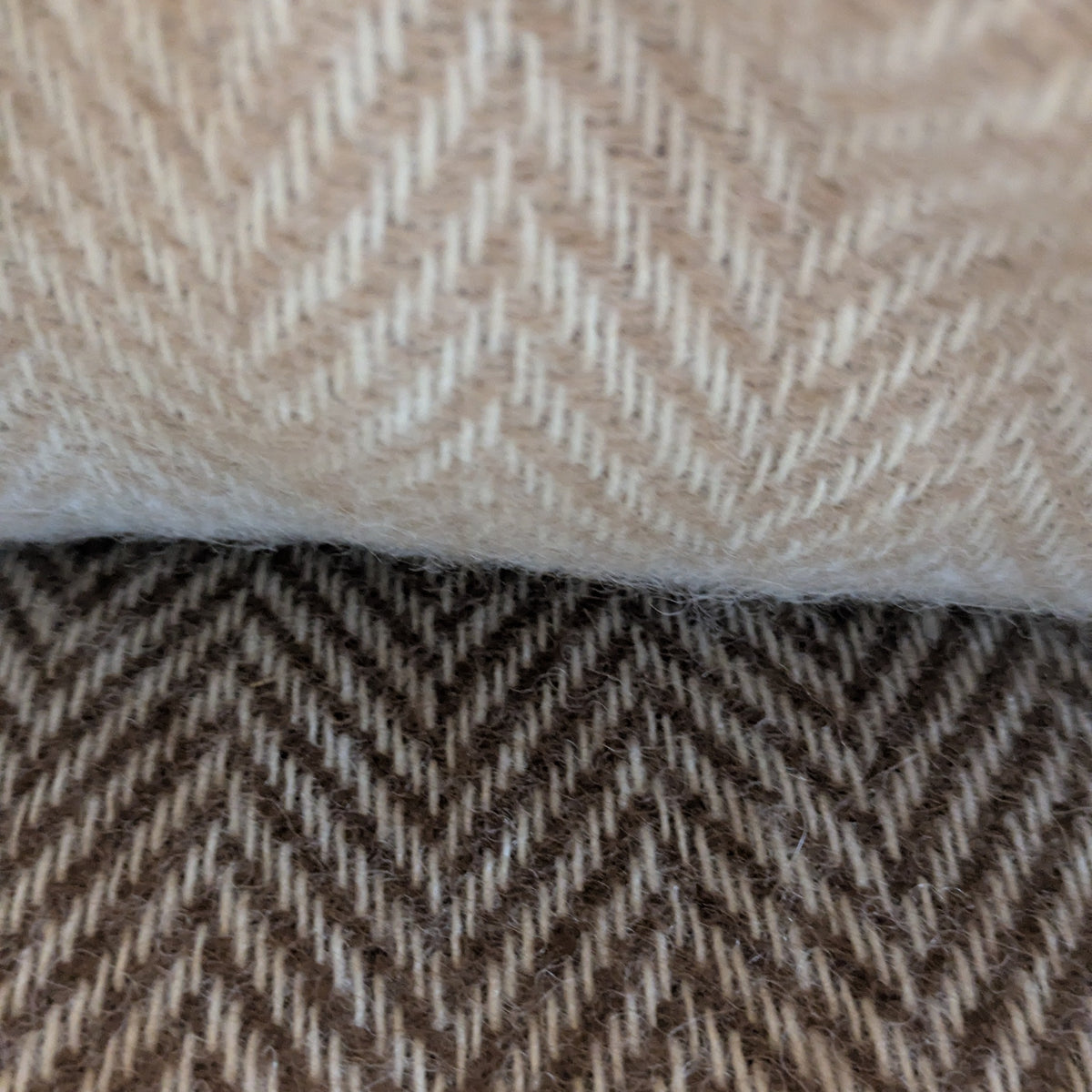 Close-up of woven alpaca textiles with a herringbone pattern, showing a fawn and cream top fabric and a brown and cream bottom fabric.
